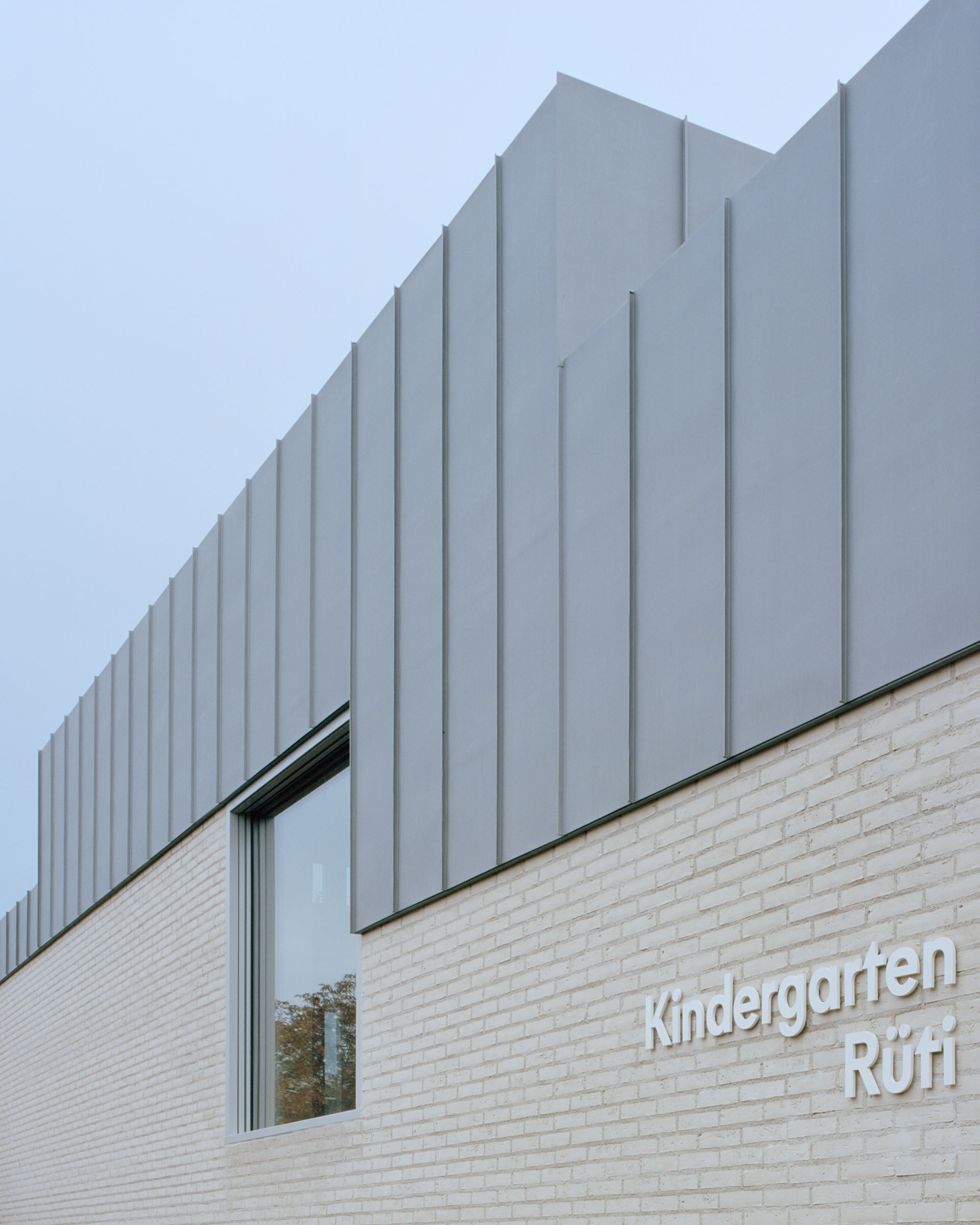 Analog architectural photography and documentation of the exterior of the Rueti kindergarten in Winkel, Switzerland, designed by Brandenberger Kloter. Photographed by Piotr Hraptovich, architectural photographer based in Basel, Switzerland. Analoge Architekturfotografie und Dokumentation der Aussensicht des Doppelkindergartens Rüti in Winkel, Schweiz, entworfen von Brandenberger Kloter. Fotografiert von Piotr Hraptovich, Architekturfotograf mit Sitz in Basel, Schweiz. 