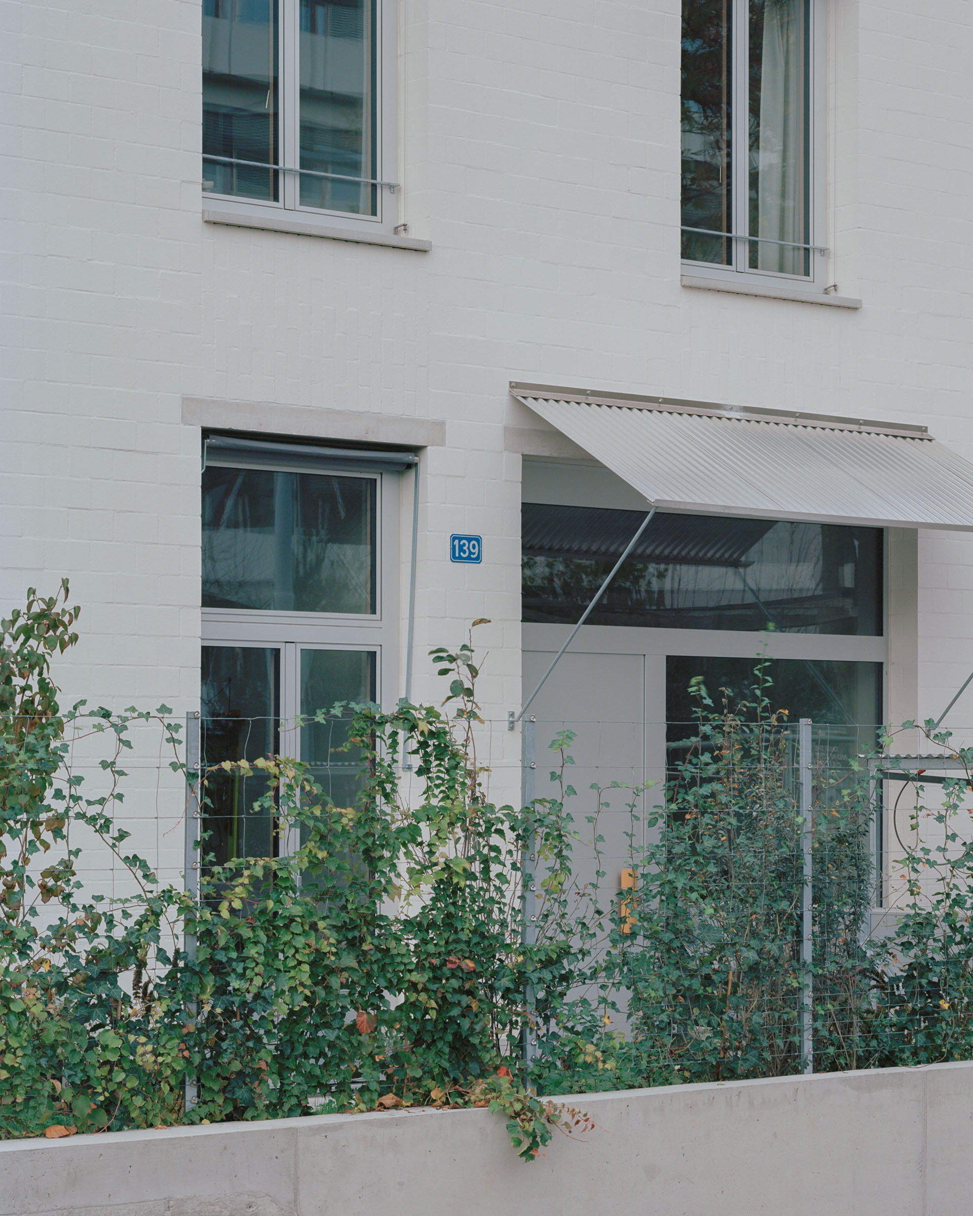 Analog architectural photography and documentation of the exterior of the residential building KGUB in Basel, Switzerland, designed by Jäger Koechlin Architekten. Photographed by Piotr Hraptovich, architectural photographer based in Basel, Switzerland. Analoge Architekturfotografie und Dokumentation der Aussensicht des Wohngebäudes KGUB in Basel, Schweiz, entworfen von Jäger Koechlin Architekten. Fotografiert von Piotr Hraptovich, Architekturfotograf mit Sitz in Basel, Schweiz. 