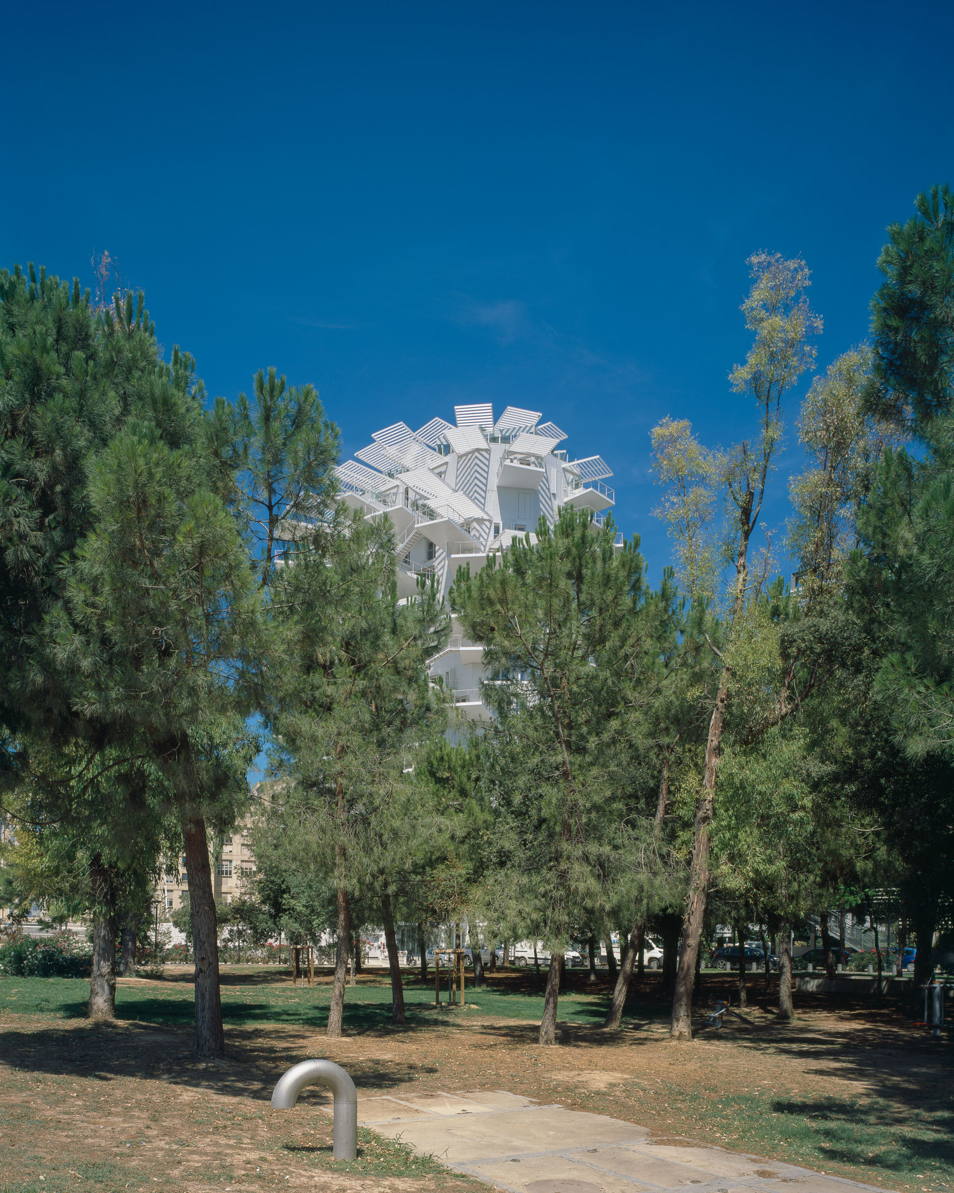 Analog architectural photography and documentation of the exterior of L’Arbre Blanc residential tower in Montpellier, France, designed by Sou Fujimoto in collaboration with Nicolas Laisné and Manal Rachdi (OXO Architects). Photographed by Piotr Hraptovich, architectural photographer based in Basel, Switzerland. Analoge Architekturfotografie und Dokumentation der Aussensicht des Wohnhochhauses L’Arbre Blanc in Montpellier, Frankreich, entworfen von Sou Fujimoto in Zusammenarbeit mit Nicolas Laisné und Manal Rachdi (OXO Architects). Fotografiert von Piotr Hraptovich, Architekturfotograf mit Sitz in Basel, Schweiz. 